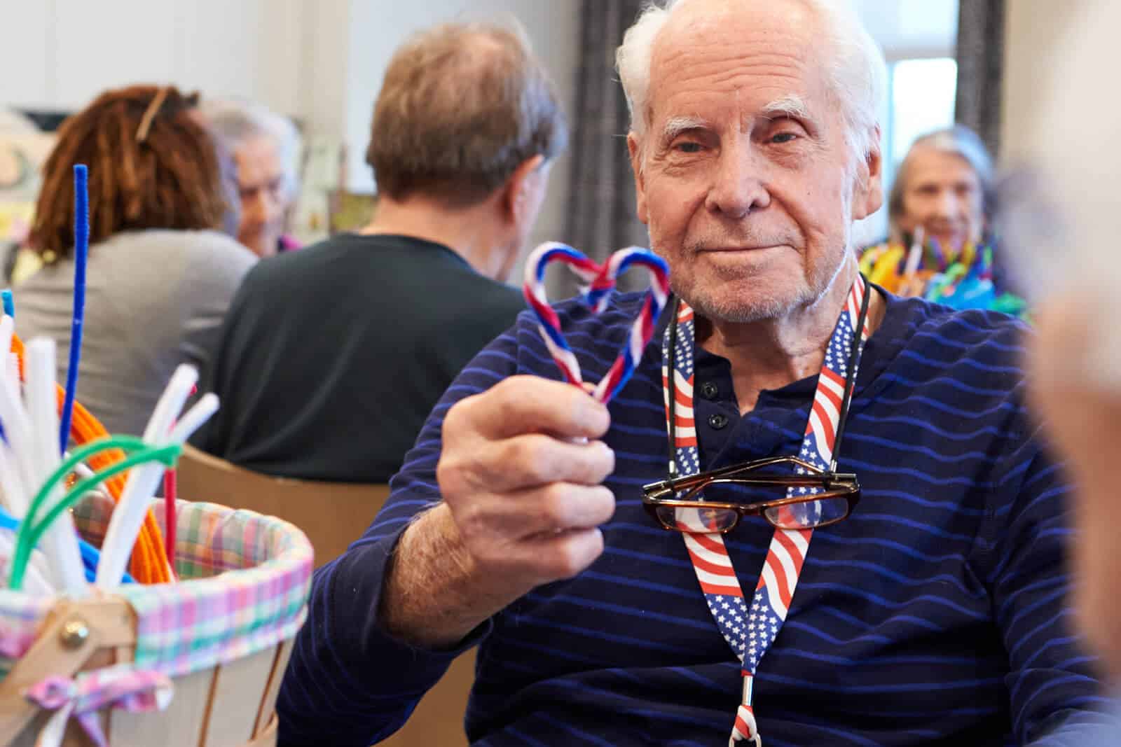 elderly man holding a red, white and blue heart that he made