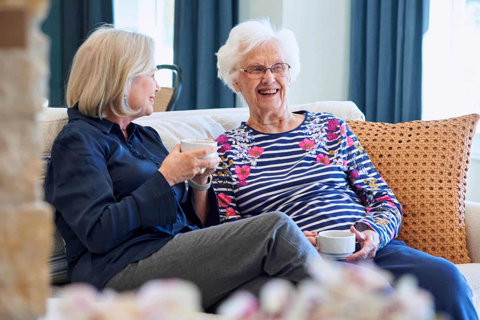 2 people sitting on the couch drinking coffee