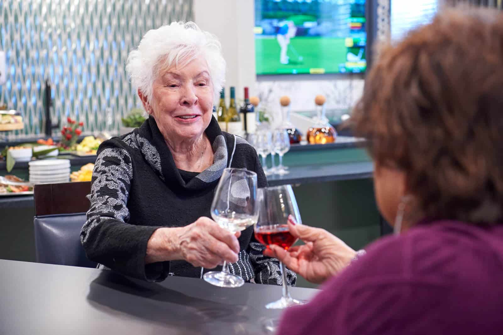 2 elderly women toasting their wine glasses