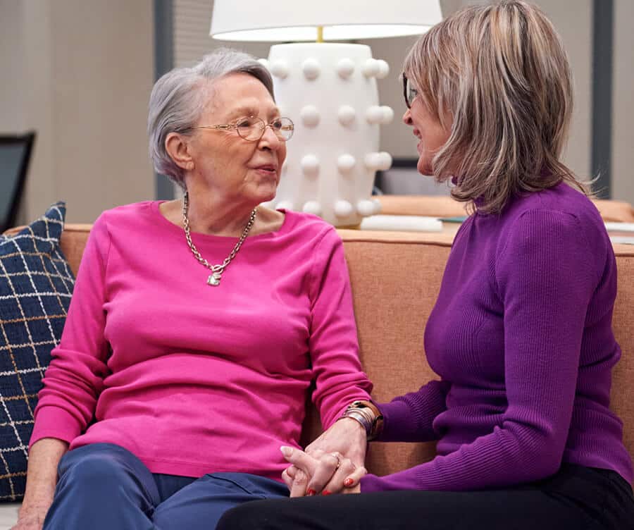 daughter and mom holding hands on a couch