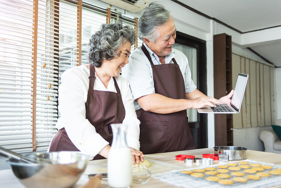 A senior couple in a kitchen baking holiday cookies together