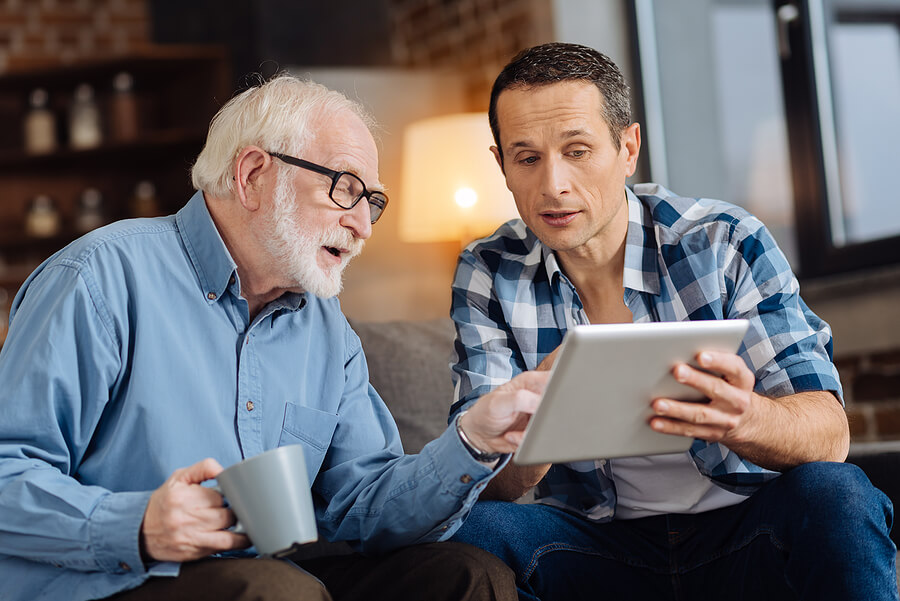 A senior man is talking with his son about senior living and researching options together.