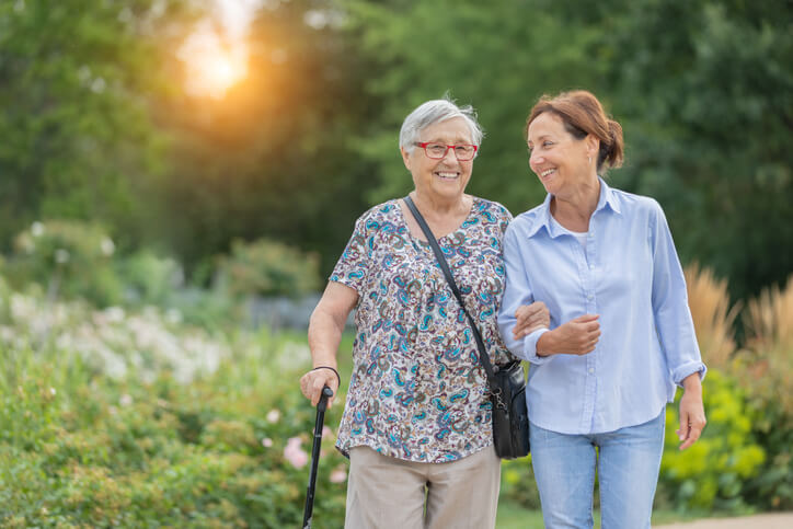 A senior woman and her daughter walking outside on a springlike day